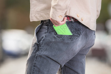 在模糊的街道上男人拿绿色智能手机图片