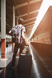 夏季旅行有手提箱的男子等待火车在火车站图片