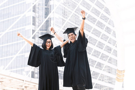 两个快乐的学生庆祝成功毕业在校园建筑背景的学图片