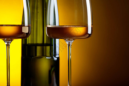 黄色背景的白葡萄酒玻璃和瓶子图片