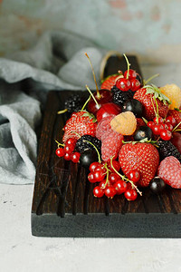 木板上的有机浆果灰色背景上的浆果夏季轻甜点健康食品夏季和健图片