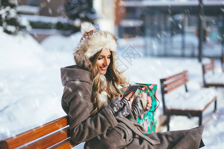 坐在长凳外的美丽的女士冬季肖像图片