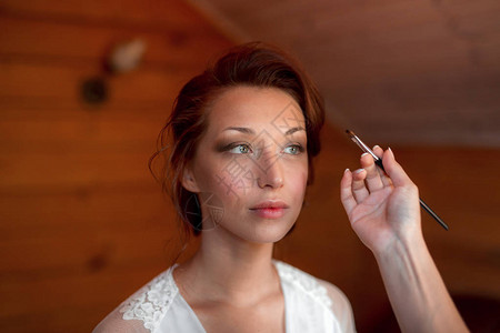 化妆过程化妆艺术家用画笔在模特脸上工作在美容沙龙内部图片