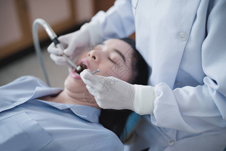 拿着牙科工具的牙医的手检查躺在医院牙科椅上图片