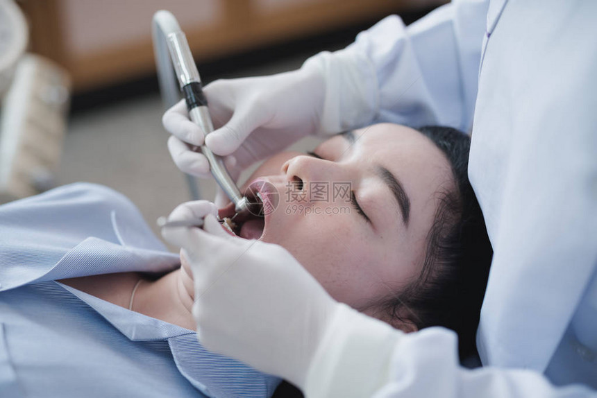 拿着牙科工具的牙医的手检查躺在医院牙科椅上图片