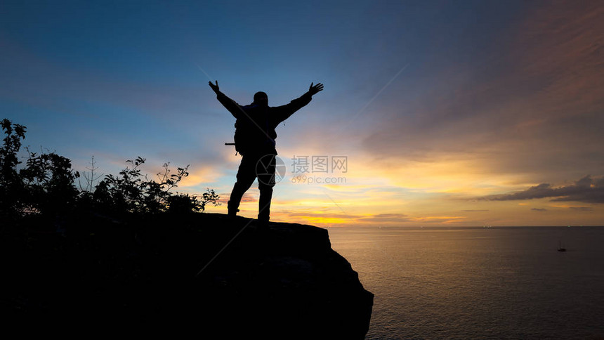 旅行者成功青年男子在山顶举手等待日出图片