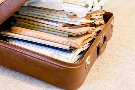 用皮革制造的老式手提箱装满了文件夹文件图片