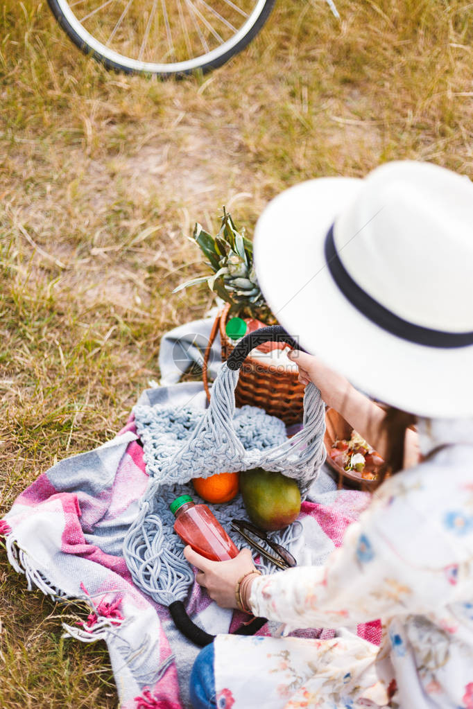 戴着白帽的年轻女士坐在野餐毯上图片