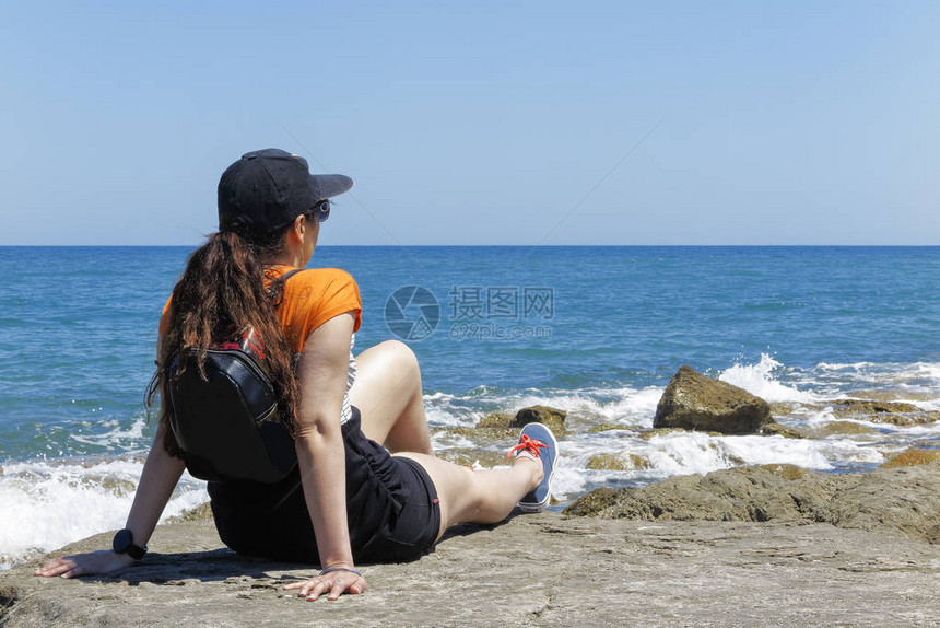 一个戴帽子对抗太阳的女人的月光躺在海滩岩石上仰望着大图片