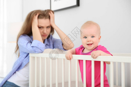 年青母亲产后抑郁症在婴儿床附近家里图片