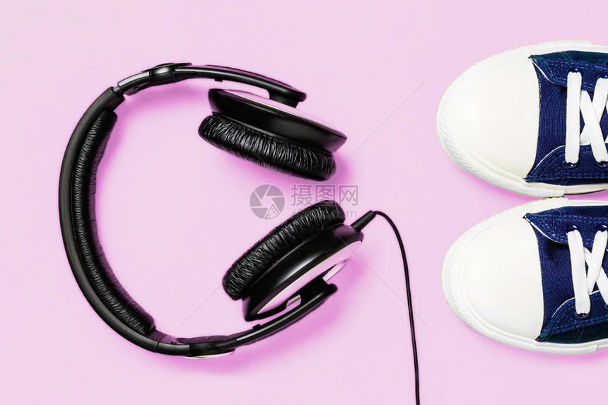 粉红明亮背景的一双新型时装运动鞋和耳机顶部视图概念走向音乐图片