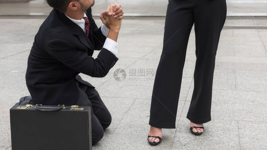 悲伤的商人在办公楼外没有得到晋升或受到惩罚后跪下举手请求同情图片