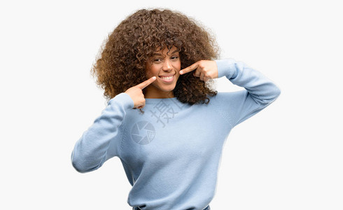 身穿毛衣的非裔美国妇女满怀自信地展示并用手指牙和嘴指着健康概图片
