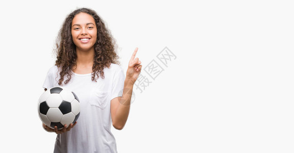 带着足球的年轻西班牙女青年非常快乐地用手和指对着图片