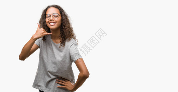 美丽的年轻西班牙裔女人戴着眼镜微笑着用手和指做电话手势图片