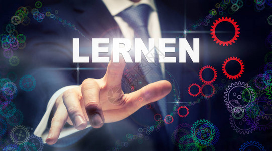 一位商人按着德国文的Lernen学习按钮在未来的计图片