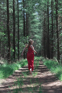 穿红裙子的金发女人从森林路上的图片