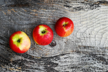 木制背景上的三个新鲜红苹果图片