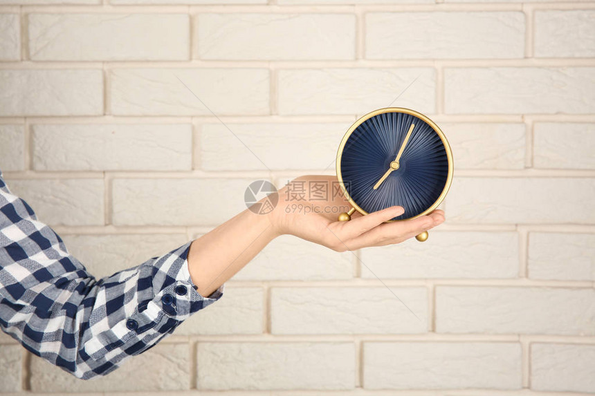 妇女在砖墙附近时钟守时图片