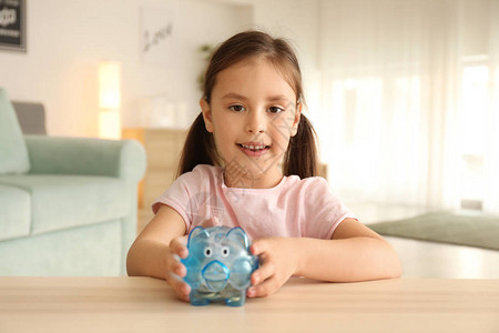 快乐的小女孩和室内小猪银行图片