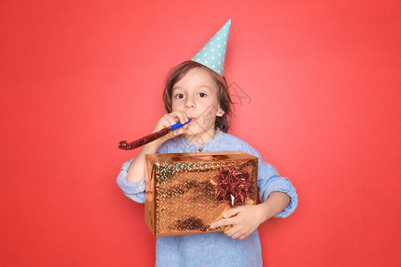 带着派对口哨和生日礼物的可爱男孩用彩色背图片