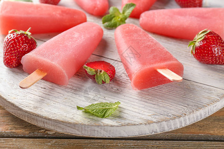 木板上有浆果的美味草莓冰棒图片