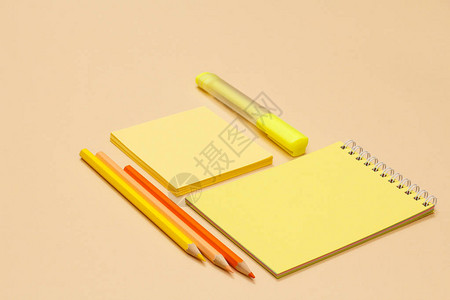 米色背景上的彩色铅笔记本便条纸和黄色毡尖笔回到学校的概念学校用品图片