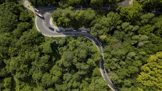 汽车沿着蜿蜒的山口公路穿过俄罗斯索契森林的空中库存照片背景图片