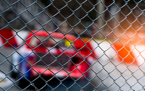 在柏油路上赛车从赛马场背景上模糊的汽车上的栅栏网看街道赛上的超级赛车背景图片