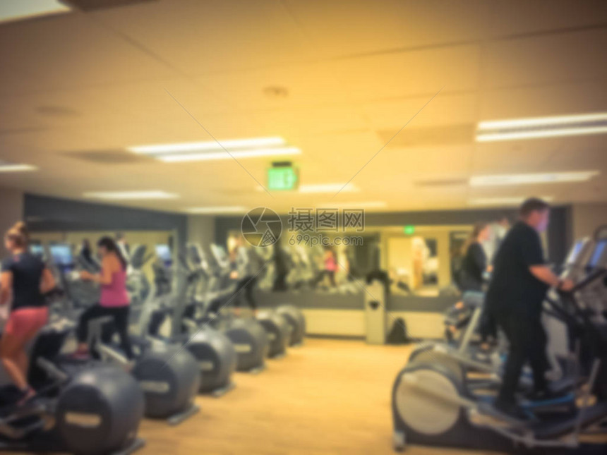 老式模糊的人在现代健身房的椭圆机和健身车上锻炼美国四星级酒店设施室内耐力设备配备训练器械的图片
