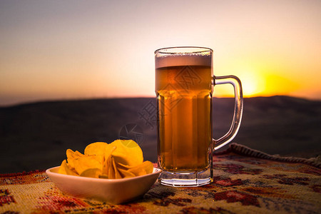 紧贴啤酒杯和日光背景的零食图片