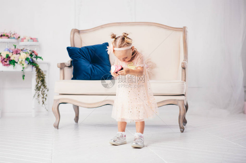 穿着粉红色连衣裙的有趣的两岁白人女孩站在房子的卧室里图片
