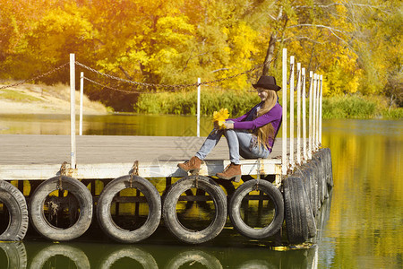 坐在河边码头的戴帽子的女孩秋图片