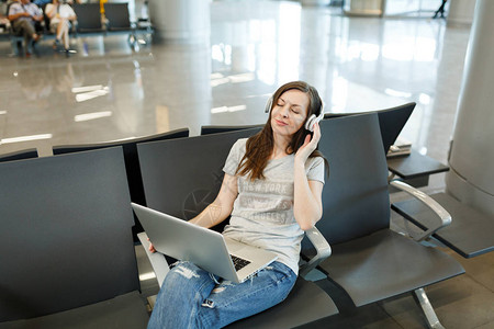 年轻松的旅游女戴着耳机在笔记本电脑上听音乐图片
