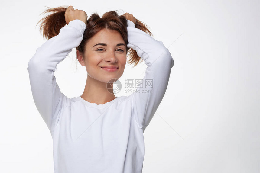 快乐的年轻女人摸着马尾的红头发图片