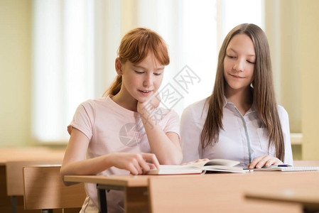 2名女学生坐在免费大学的书桌旁背景图片