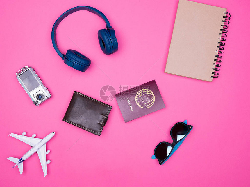在粉红背景笔记本护照钱包耳机太阳镜上图片
