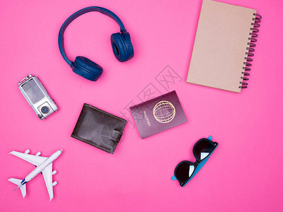 在粉红背景笔记本护照钱包耳机太阳镜上图片
