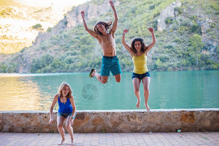 朋友们在山上绿松石湖的堤岸上跳跃图片