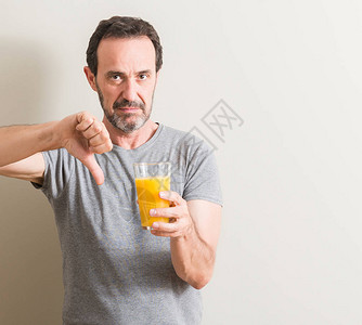 高年男子在杯子里喝橙汁图片