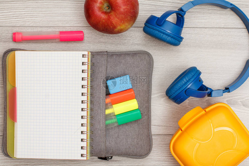 用彩色毡笔和记号笔苹果耳机和灰色木制背景上的午餐盒打开袋子铅笔盒上的笔记本带有复制空间的顶视图回到学校的概图片