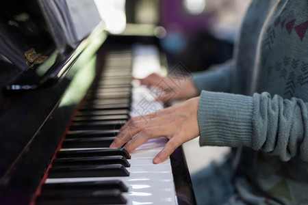 女钢琴手在经典钢琴键盘上玩耍关闭对音乐器的手指家庭概念中图片