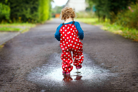 蹒跚学步的小女孩穿着雨靴和裤子图片