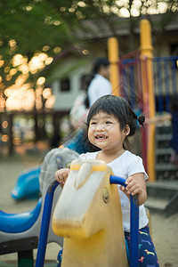 小女孩在公园的操场玩旋转木马在公图片