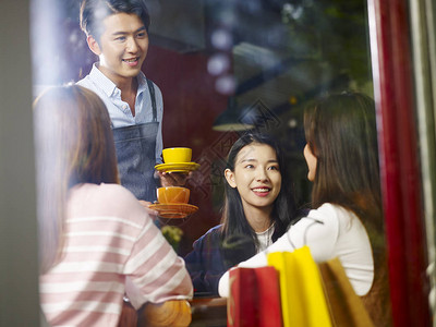 年轻的服务生在咖啡店为女顾客服务被图片
