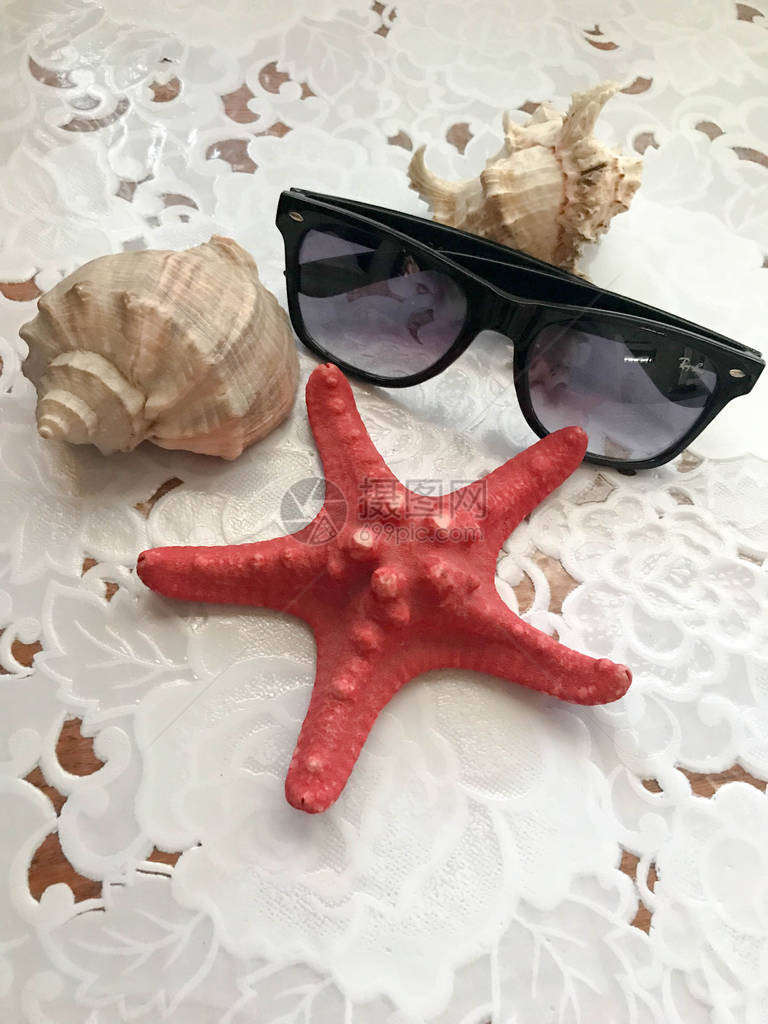 美丽的红海星和黑太阳镜被装饰在白布底的贝壳上海洋热带夏季背景笑声图片