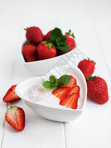 白色木桌上的草莓酸奶碗图片