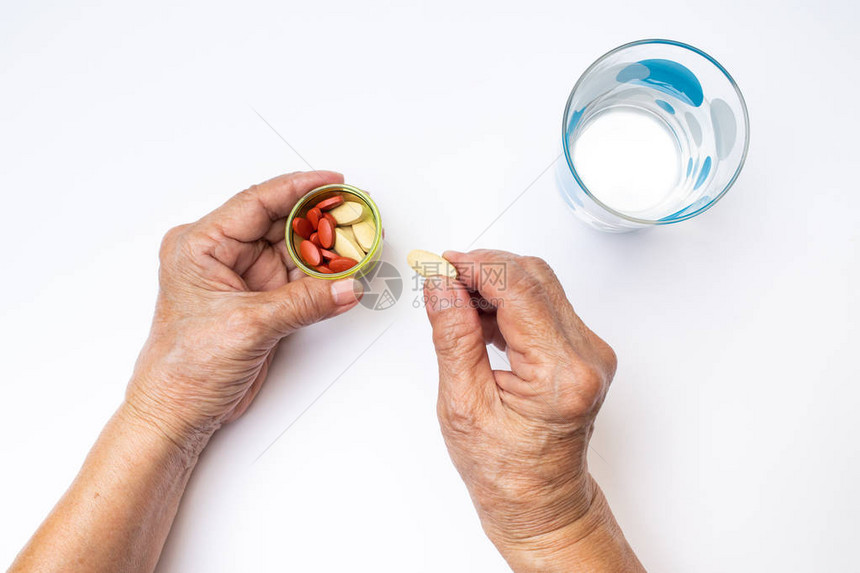 老年妇女的手拿着瓶中的维生素C丸和抗贫血丸图片