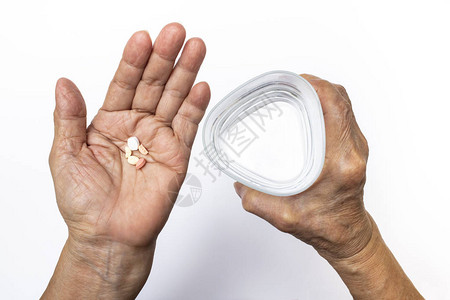 高龄妇女用三边杯水保健和医疗概念的药丸握着图片