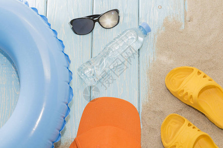 在海滩上放暑假黄色翻滚式拖鞋和游泳圈图片